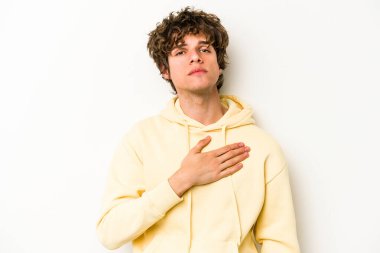 Beyaz arka planda izole edilmiş genç beyaz adam yemin ediyor, elini göğsüne koyuyor..