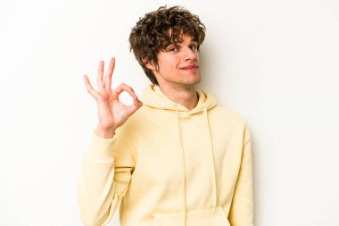 Beyaz arka planda izole edilmiş genç beyaz bir adam bir göz kırptı ve elleriyle iyi bir jest yaptı..