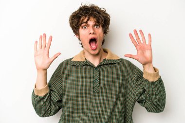Beyaz arka planda izole genç beyaz adam hoş bir sürpriz alıyor, heyecanlı ve el kaldırıyor..