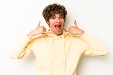 Beyaz arka planda izole edilmiş genç beyaz bir adam parmakları olan bir cep telefonu hareketi gösteriyor..