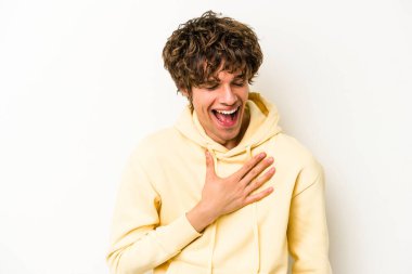 Beyaz arka planda izole genç beyaz adam yüksek sesle gülüyor elini göğsüne koyuyor..
