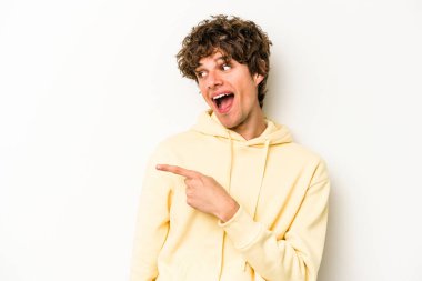 Beyaz arka planda izole edilmiş genç beyaz adam gülümseyen, neşeli ve keyifli bir tarafa bakıyor..