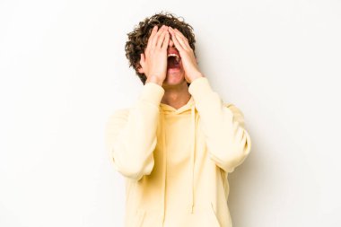 Beyaz arka planda izole olmuş genç beyaz bir adam ellerini başının üstünde tutarak neşeyle gülüyor. Mutluluk kavramı.