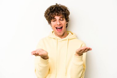 Beyaz arka planda izole edilmiş genç beyaz bir adam elinde avuç içi bir şeyle kameraya sunuyor..