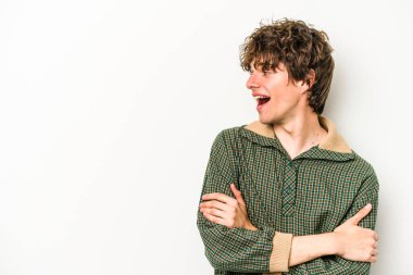 Beyaz arka planda izole edilmiş genç beyaz adam kollarını kavuşturarak gülümsüyor..