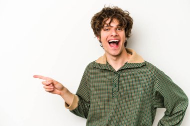 Beyaz arka planda izole edilmiş genç beyaz adam işaret parmağıyla işaret ederek gülümsüyor..