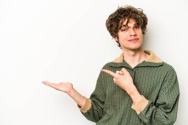 Beyaz arka planda izole edilmiş genç beyaz bir adam, palmiye üzerinde bir fotokopi alanı tutarken heyecanlı..