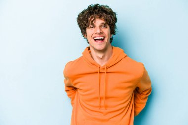 Mavi arka planda izole edilmiş genç beyaz adam mutlu, güler yüzlü ve neşeli.