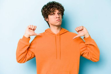 Mavi arka planda izole edilmiş genç beyaz adam gururlu ve kendinden emin hissediyor, örnek olarak.