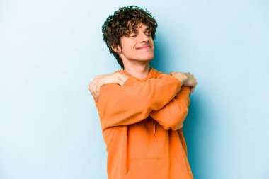 Kafkasyalı genç adam mavi arka planda izole edilmiş, güler yüzlü ve mutlu..