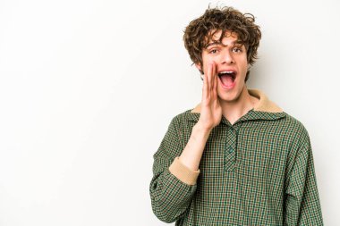 Beyaz arka planda izole genç beyaz adam yüksek sesle bağırıyor, gözleri açık ve elleri gergin tutuyor..