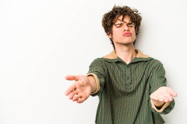 Beyaz arka planda izole edilmiş genç beyaz bir adam dudaklarını katlıyor ve hava öpücüğü vermek için avuç içleri tutuyor..