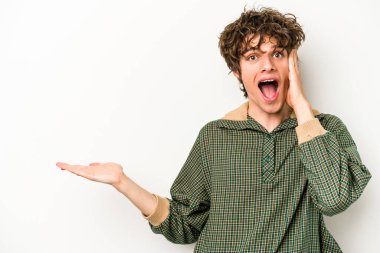 Beyaz arka planda izole edilmiş genç beyaz bir adam bir avuç içinde fotokopi alanı tutuyor, el üstünde tutuyor. Şaşırmış ve mutlu..