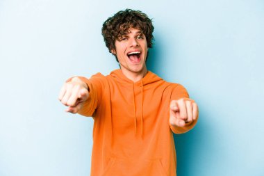 Mavi arka planda izole edilmiş genç beyaz adam öne bakan neşeli gülümsemeler.