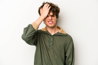 Beyaz arka planda izole edilmiş genç beyaz bir adam bir şeyi unutuyor. Alnına avuç içi ve gözlerini kapayarak vuruyor..