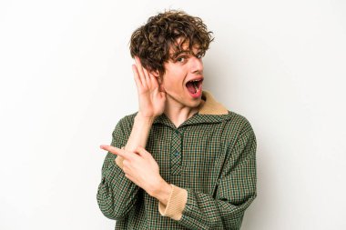 Beyaz arka planda izole edilmiş genç beyaz adam bir dedikoduyu dinlemeye çalışıyor..