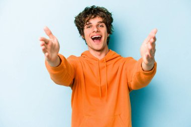 Mavi arka planda izole edilmiş beyaz bir genç hoş bir yüz ifadesi sergiliyor..