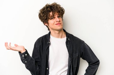 Beyaz arka planda izole edilmiş genç beyaz bir adam sorgulama sırasında omuz silkiyor ve şüphe duyuyor..