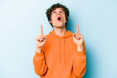 Mavi arka planda izole edilmiş beyaz bir adam ağzı açık bir şekilde üst tarafı işaret ediyor..