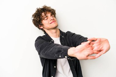 Beyaz arka planda izole edilmiş genç beyaz adam kollarını uzatıyor, rahat bir konumda..