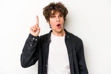 Beyaz arka planda izole edilmiş genç beyaz adam ağzı açık bir şekilde üst tarafı işaret ediyor..