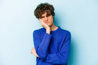Mavi arka planda izole edilmiş, sıkılmış, yorgun ve dinlenmeye ihtiyacı olan genç beyaz bir adam..