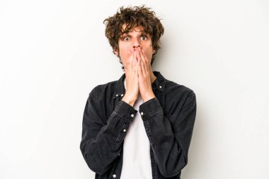 Beyaz arka planda izole edilmiş genç beyaz adam elleriyle ağzını kapatırken şok oldu..