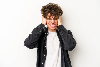 Beyaz arka planda izole edilmiş genç beyaz bir adam kulaklarını elleriyle kapatıyor..