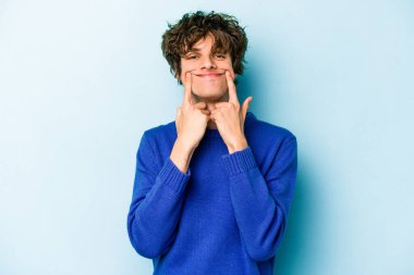 Kafkasyalı genç adam mavi arka planda izole edilmiş iki seçenek arasında şüphe duyuyor.