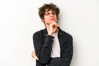 Beyaz arka planda izole edilmiş genç beyaz bir adam şüpheli, belirsiz, seni muayene ediyor..