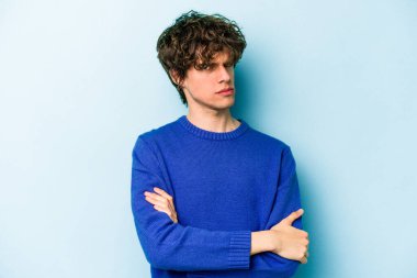 Kafkasyalı genç adam mavi arka planda izole edilmiş şüpheli, belirsiz, seni muayene ediyor..