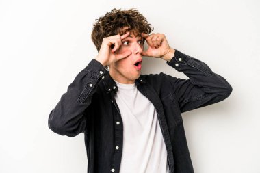 Beyaz arka planda izole edilmiş genç beyaz bir adam bir başarı fırsatı bulmak için gözlerini açık tutuyor..