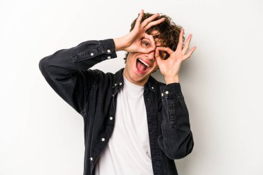 Beyaz arka planda izole edilmiş genç beyaz bir adam gözlerinde sorun olmadığını gösteriyor.