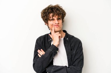 Beyaz arka planda izole edilmiş genç beyaz adam alaycı bir ifadeyle kameraya bakıyor..