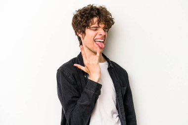 Beyaz arka planda izole edilmiş genç beyaz bir adam parmaklarıyla kaya hareketi gösteriyor.