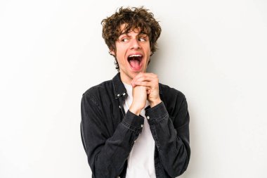 Beyaz arka planda izole genç beyaz adam ellerini çenesinin altında tutuyor, mutlu bir şekilde yana bakıyor..