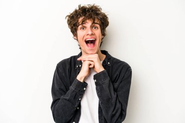 Beyaz arka planda izole edilmiş genç beyaz bir adam şans için dua ediyor, şaşırmış ve ağzını açıp önüne bakıyor..