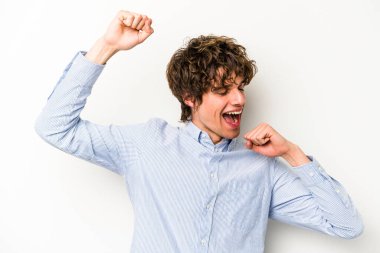 Beyaz arka planda izole genç beyaz adam özel bir günü kutluyor, atlıyor ve enerjiyle kollarını kaldırıyor..