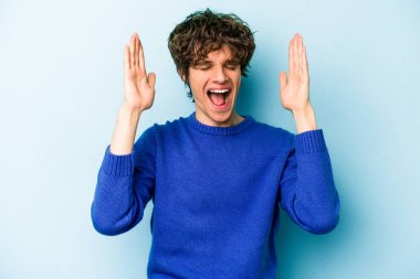 Kafkasyalı genç adam mavi arka planda izole edilmiş neşeli bir şekilde gülüyor. Mutluluk kavramı.