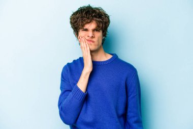 Mavi arka planda izole genç beyaz adam güçlü bir diş ağrısı, azıdişi ağrısı var..