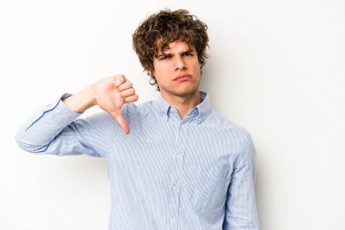 Beyaz arka planda izole edilmiş genç beyaz bir adam baş parmağını aşağı gösteriyor ve hoşlanmadığını ifade ediyor..