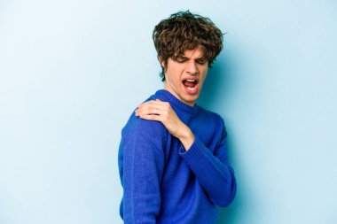 Mavi arka planda izole edilmiş, omuz ağrısı olan genç beyaz bir adam..