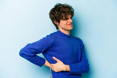 Mavi arka planda izole edilmiş beyaz bir adam sırt ağrısı çekiyor..