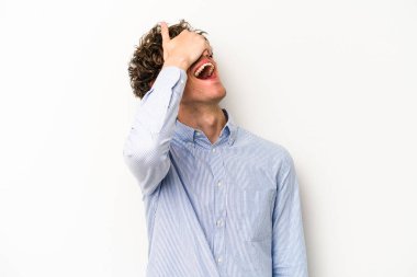 Beyaz arka planda izole olmuş genç beyaz bir adam ellerini başının üstünde tutarak neşeyle gülüyor. Mutluluk kavramı.