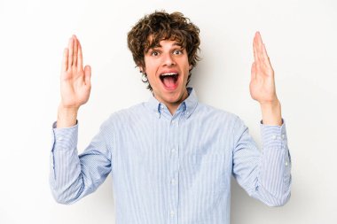Beyaz arka planda izole genç beyaz adam hoş bir sürpriz alıyor, heyecanlı ve el kaldırıyor..