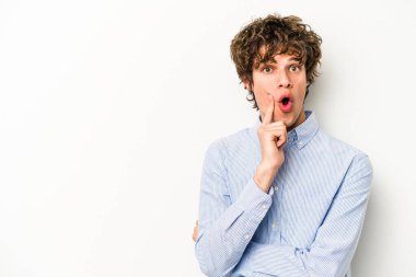 Beyaz arka planda izole edilmiş genç beyaz bir adam şüpheli ve şüpheci bir ifadeyle yana bakıyor..