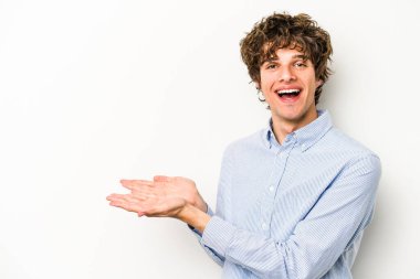 Beyaz arka planda izole edilmiş beyaz tenli genç bir adam palmiyesinde bir kopya alanı tutuyor..