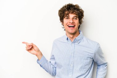 Beyaz arka planda izole edilmiş genç beyaz adam işaret parmağıyla işaret ederek gülümsüyor..