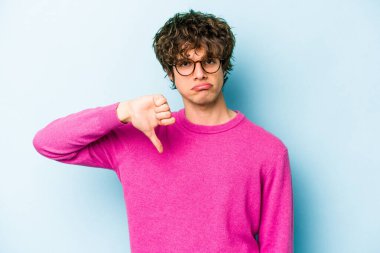 Mavi arka planda izole edilmiş genç beyaz bir adam hoşlanmadığı bir jest yapıyor. Anlaşmazlık konsepti.