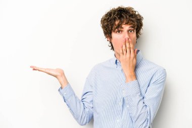 Beyaz arka planda izole edilmiş genç beyaz adam, avuç içi fotokopi alanını elinde tutmaktan etkilenmiş..